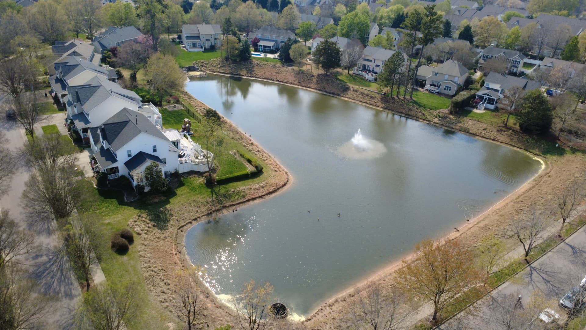 Aerial view of Bedford homes around a pond with a fountain